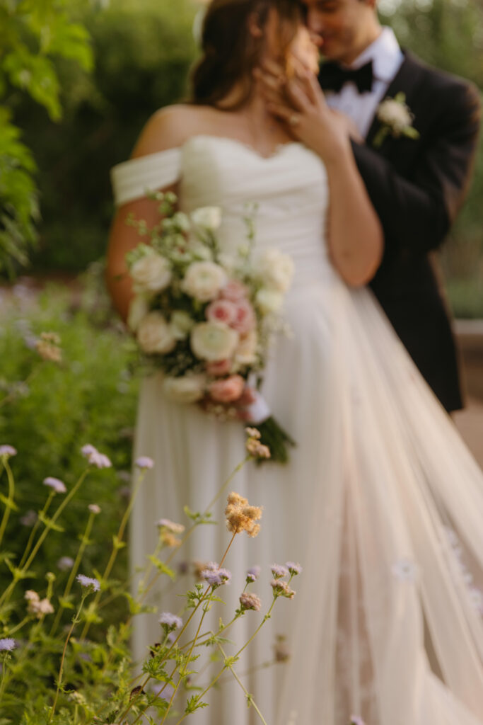Couple embracing among desert blooms during their Desert Botanical Garden wedding