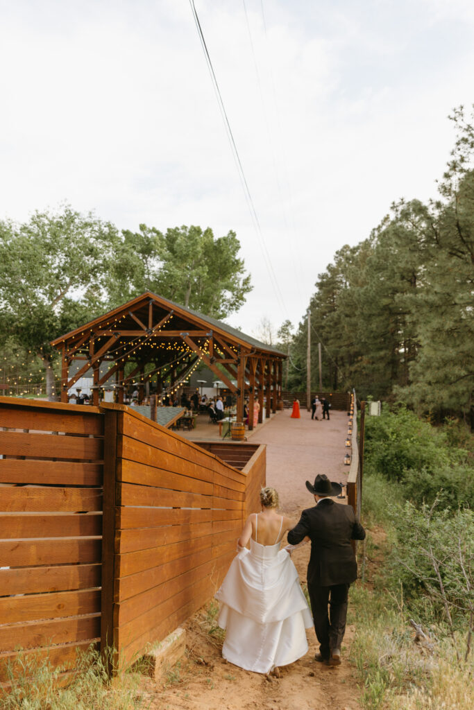 Bride and groom walking through pine trees at Cabins on Strawberry Hill
