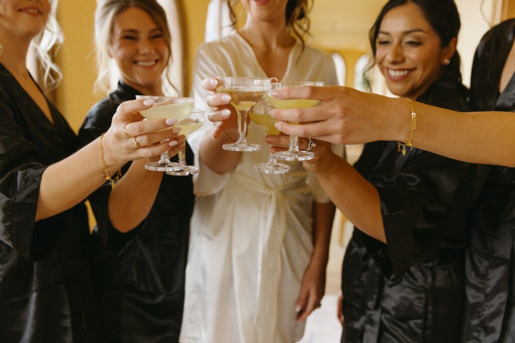 bride with bridesmaids holding champagne