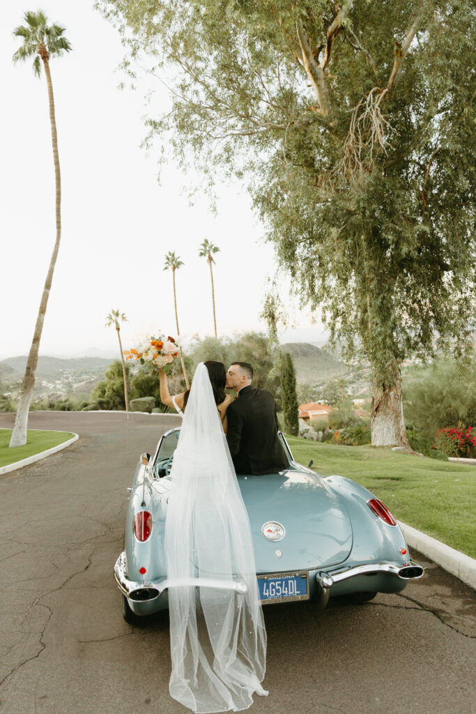 Newlyweds celebrating beside a vintage car at Different Pointe of View
