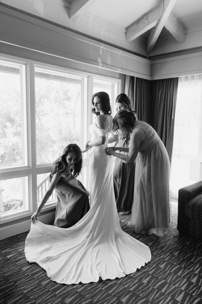 Bride smiling while putting on her wedding dress before the ceremony.