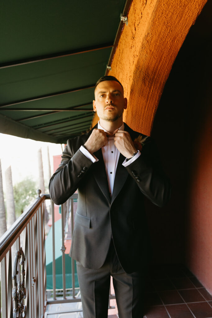 Groom adjusting his tie while getting ready at Hilton Phoenix Tapatio Cliffs Resort.