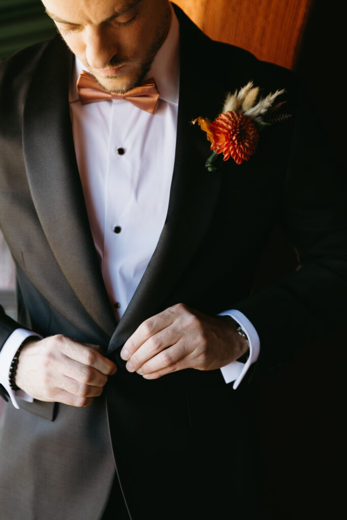 Groom adjusting his tie while getting ready at Hilton Phoenix Tapatio Cliffs Resort.